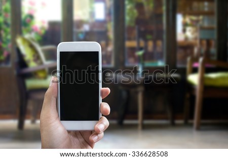 Man's hand shows mobile smartphone in vertical position, blurred background - mockup template