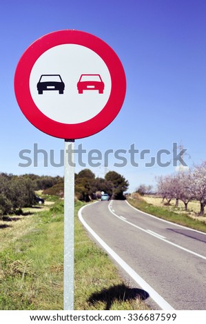 no overtaking sign in a secondary road bordered for olive trees and almond trees in full bloom