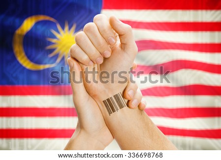 Barcode ID number on wrist of a human and national flag on background - Malaysia