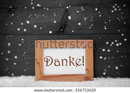 Gray Christmas Card With Brown Picture Frame On White Snow With Snowflakes. German Text Danke Means Thank You. Rustic Wooden, Vintage Background. Black And White