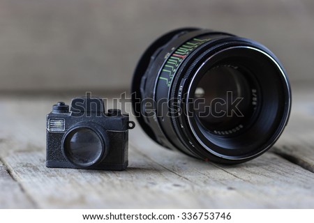 Close-up view of old small toy camera and camera lens on wooden background
