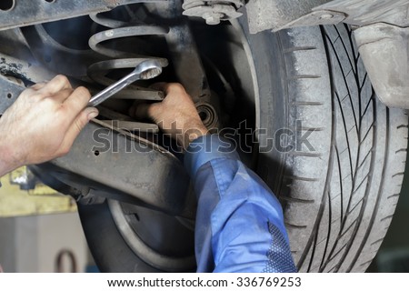 Hands mechanics to repair the suspension on the car Royalty-Free Stock Photo #336769253