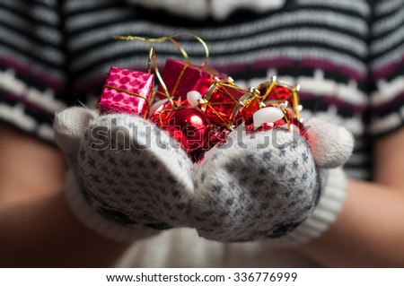 Christmas decorations in the hands of a girl. Woman holding a Christmas Decorations. Knitted mittens. Knitted dress. Christmas background. New Year background.
