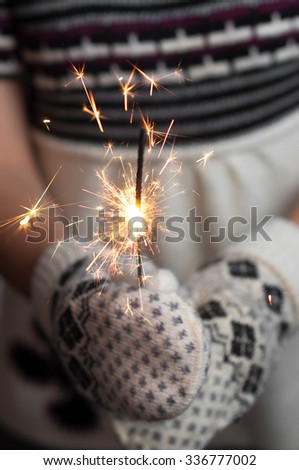 Christmas decorations in the hands of a girl. Woman holding a Christmas Decorations. Woman holding a sparkler. Knitted mittens. Knitted dress. Christmas background. New Year background.