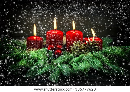 Advent decoration. Four red burning candles, ornaments and christmas tree branches. Vintage style dark toned picture with falling snow effect