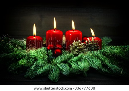 Advent decoration. Four red burning candles, ornaments and christmas tree branches. Vintage style toned picture