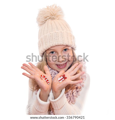 Happy girl demonstrating painted Christmas symbols on her hands. 
