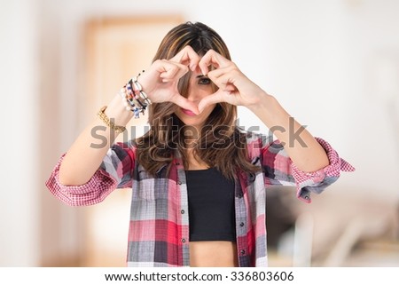 Girl making a heart with her hands over unfocused background