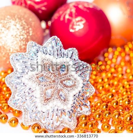 Christmas holiday decoration. Orange, red ornament bauble, snowflake with gold beads background. Festive merry xmas, new year celebration. Golden shiny light decorative closeup ball. 