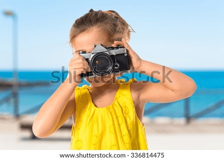 Blonde little girl photographing something on unfocused background