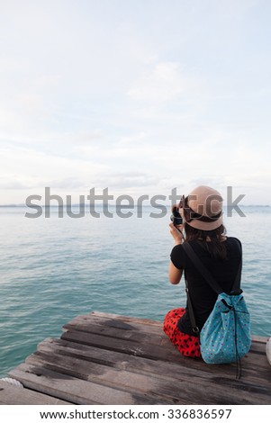Woman photographing sea Sitting on a wooden bridge by the sea. A quiet sea