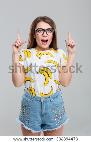 Portrait of a happy thoughtful woman pointing fingers up isolated on a white background