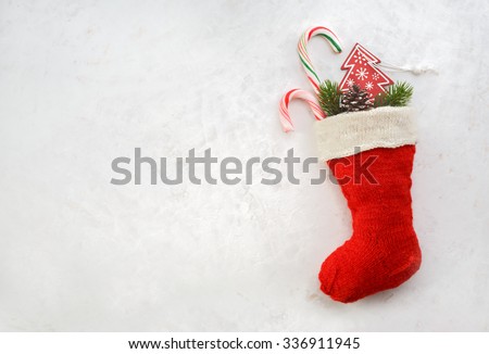 Holidays symbol stocking. Red christmas sock with gifts on a light background. Christmas background with copyspace