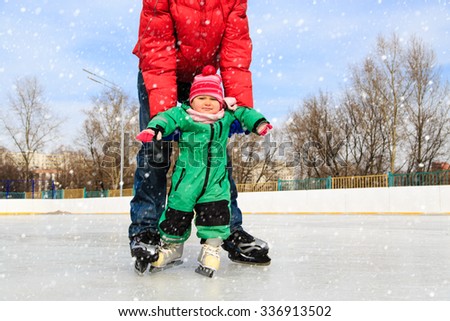 father and child learning to skate in winter snow