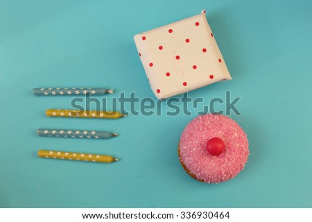 Cupcake, candle and gift box on blue background