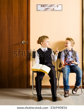 Two schoolboys are sitting next to principal's office. They are twin, but they have different each other behavior and clothes. For creating this picture were used two image of one and the same boy.