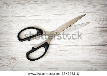 One office scissors on the wooden background. Office supplies. Detail photo.
