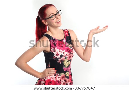 portrait of a pretty red haired girl wearing thick glasses and a flower print dress, holding hands on hips smiling and looking at the camera. Isolated on white background.Isolated on white background.