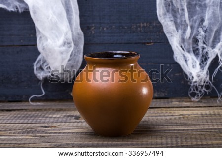 Photo still life closeup one whole terra-cotta brown clay pot standing on wooden table over blue rustic background, horizontal picture 