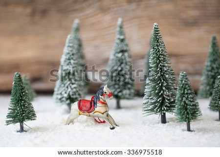 Christmas card - a miniature Christmas tree and rocking horse in the snow - winter