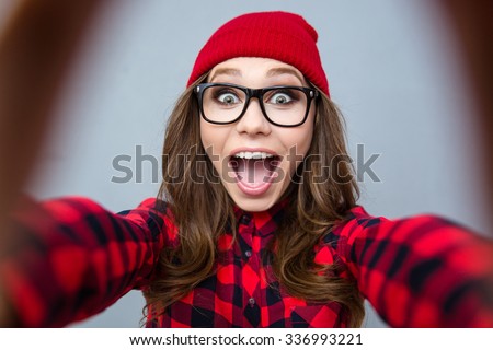 Portrait of a cheerful woman making selfie photo over gray background