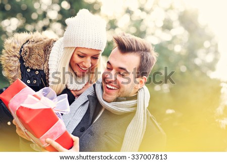 A picture of a young couple with a present in the park