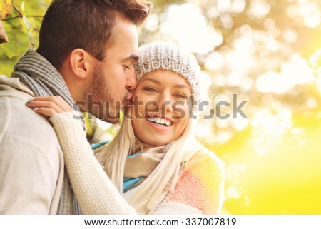 A picture of a young romantic couple kissing in the park in autumn