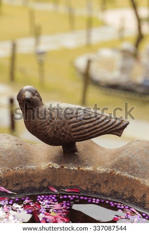 A rusted iron bird statue for garden decoration with purple fruits on the water at the fall(autumn).