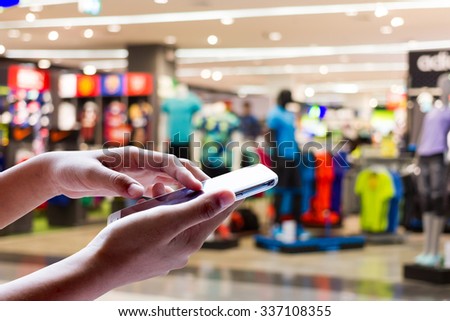 Women are using smart phone, A blurring of the product on the shelves in the background .