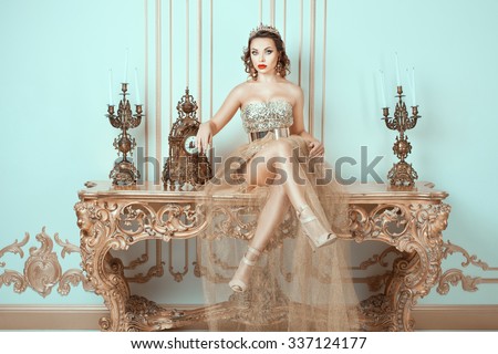 Girl with a crown on his head sitting on an old table.  Her fashion image of the queen. Royalty-Free Stock Photo #337124177