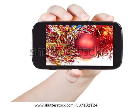 hand holds smartphone with Christmas decorations on screen isolated on white background