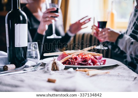 Restaurant or bar table with plate of appetizers and wine. Two people talking on background Royalty-Free Stock Photo #337134842