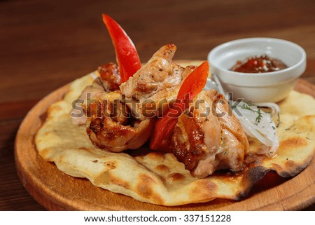 Appetizing meat dish of oriental cuisine. Meat with vegetables on pita bread. Beautiful presentation sauce. Photo for culinary magazines, posters, backdrops and websites.
