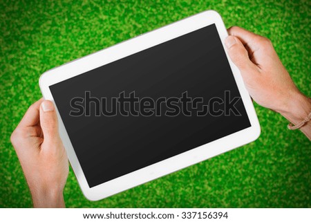 Man's hands using device against the grass