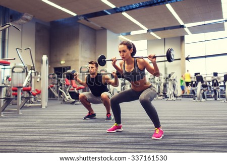 sport, bodybuilding, lifestyle and people concept - young man and woman with barbell flexing muscles and making shoulder press squat in gym Royalty-Free Stock Photo #337161530