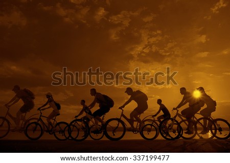 Image of sporty company friends on bicycles outdoors against sunset. Silhouette A lot phases of motion go of eight 8 cyclist along shoreline coast Reflection sun on water Copy Space for inscription