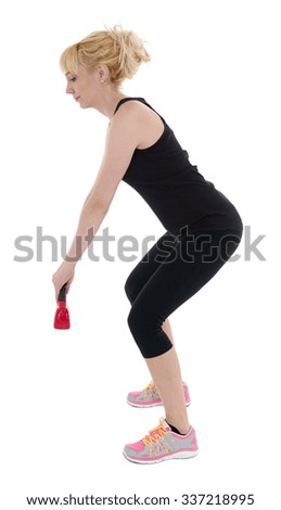 Young fitness female exercise with kettle bell. Mixed race woman doing crossfit workout on grey background. Kettlebell swing.
