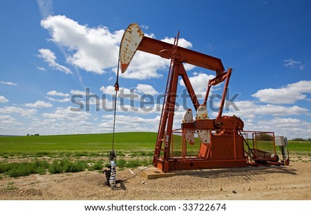 Red Oil field pump jack on the prairie