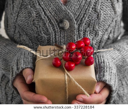 Female Holding Rustic Decorated Christmas Gift with Red Berries Bunch