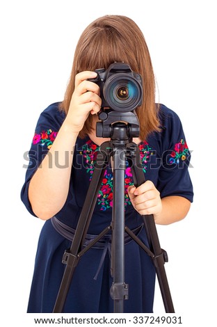 Woman photographer looking into the camera lens on a tripod isolated on white background
