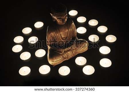 Wooden statue of Buddha with candles around him