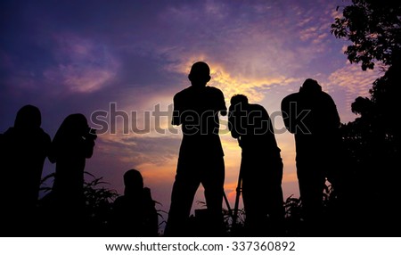 silhouette of a group of photographer who shoots a sunset in the mountains