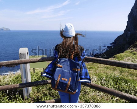 Behind the young woman standing at the view point