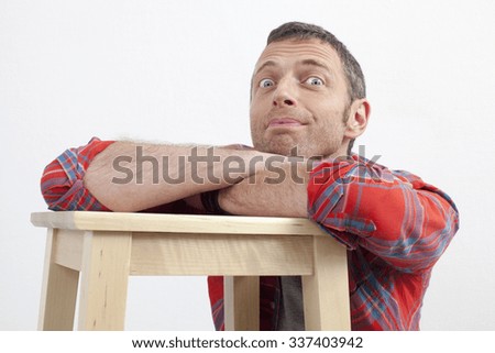 expressive casual man concept - cheerful middle age man with checked shirt leaning on wooden stool expressing excitement and happiness,white background