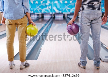 Young people in casualwear standing in bowling alley