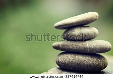 Stacked spa stones with a nature green background. Royalty-Free Stock Photo #337414964