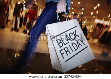 Modern shopper with Black Friday paperbag going in the mall Royalty-Free Stock Photo #337424894