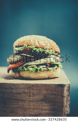 Classic american burger on wooden board. Toned picture. Selective focus and shallow DOF