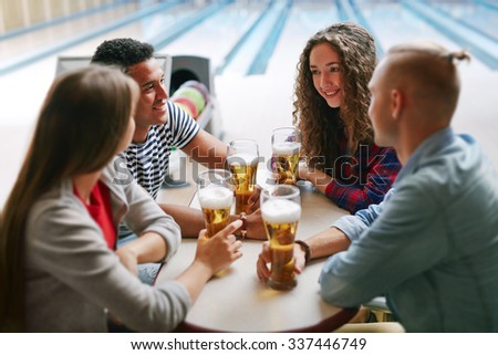 Group of friends drinking beer in bowling club