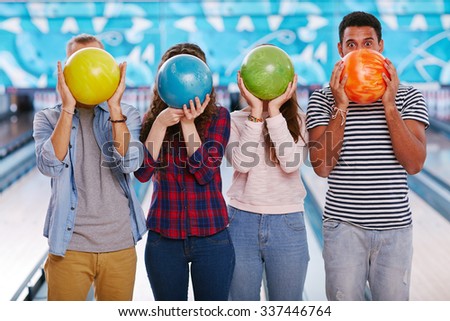 Teenagers hiding their faces behind bowling balls